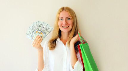 Portrait of happy smiling caucasian young woman posing with shopping bags holding cash money in...