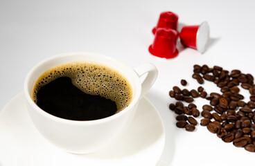 Coffee cup with fresh raw beans and coffee capsules on white background