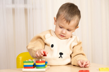 A two-year-old boy plays with wooden toys to develop logic and motor skills
