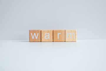 Wooden blocks form the text "Warm" against a white background.