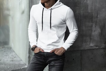 Man in a white hoodie poses for a mock-up design. A fashion template for print and branding. An...