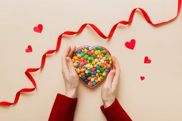 Foto op Canvas Female hands with delicious candies in box on color background © sosiukin