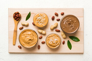 Glass jar with peanut butterin plate on table background, top view space for text and close up