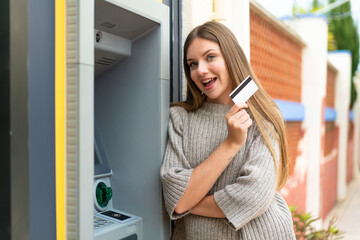 Fototapeta na wymiar Young pretty blonde woman using an ATM