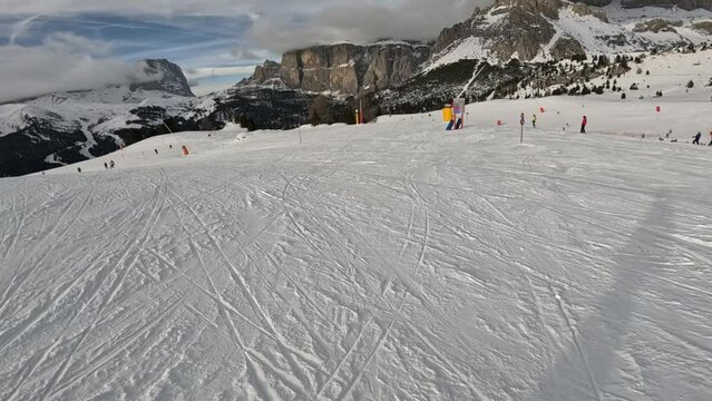 People skiing and snowboarding down the ski slope or piste in the mountains. Winter ski holidays.
