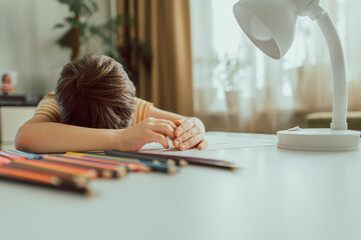 Sad boy leaning head on desk at home