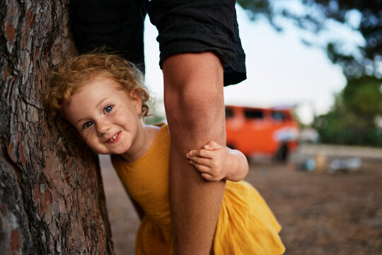 Cute girl playing with legs of her elder brother in park