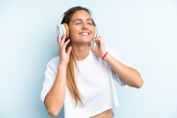 Naklejka premium Young caucasian woman isolated on blue background listening music and singing