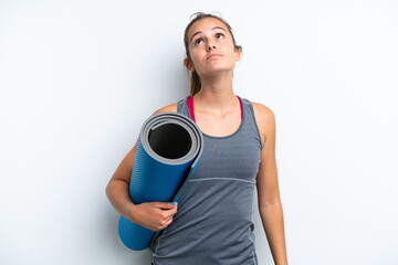 Young sport woman going to yoga classes while holding a mat isolated on white background and...