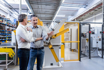 Businessman discussing with colleague in factory