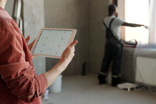 Engineer holding tablet PC with coworker in background at construction site