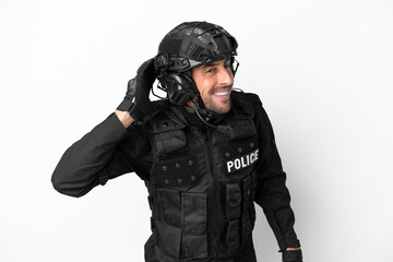 SWAT caucasian man isolated on white background listening to something by putting hand on the ear