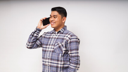 Asian young man showing happy face expression while talking on smartphone. studio shots against white background