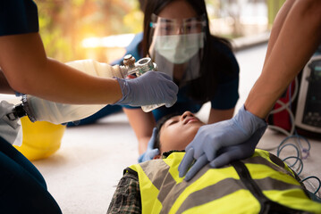 First aid, CPR, Rescue teams save lives by starting compressions using both hands and manual medical ventilators, Workers receiving cardiopulmonary resuscitation in an accident at construction work.