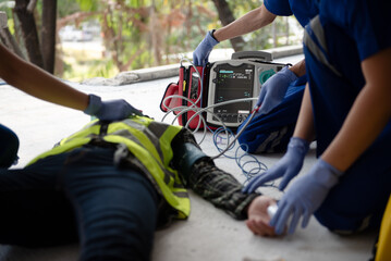 Rescuers are using equipment to check the body's pulse of worker at construction sites while unconscious and lying on the floor. Reading heartbeat with an oximeter and preparing defibrillator.