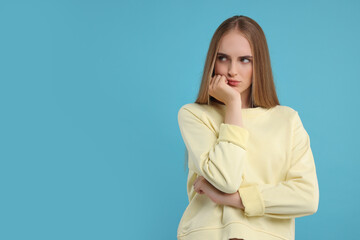 Resentful woman on light blue background, space for text