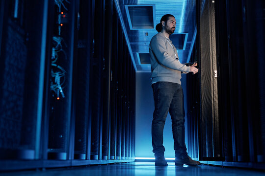 Young IT engineer examining supercomputer equipment in server room