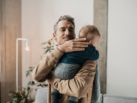 Smiling father embracing boy in arms at home