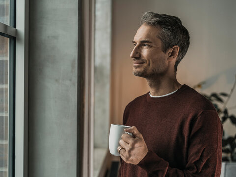 Thoughtful Man Holding Coffee Cup At Home