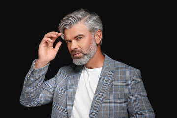 Portrait of confident man with beautiful hairstyle on black background