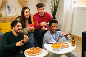Group of friends eating pizza and watching a movie in a shared student house.
