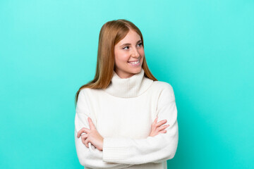 Fototapeta premium Young redhead woman isolated on blue background with arms crossed and happy