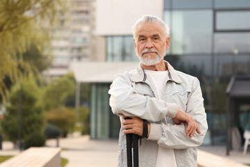 Senior man with Nordic walking poles outdoors, space for text