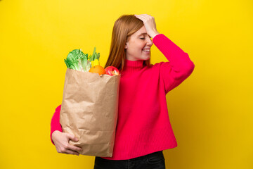 Young redhead woman holding a grocery shopping bag isolated on yellow background has realized something and intending the solution