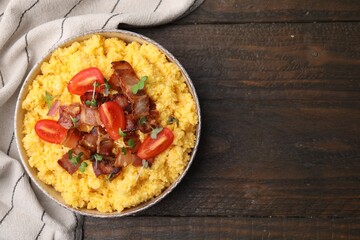 Tasty cornmeal with tomatoes, bacon and microgreens in bowl on wooden table, top view. Space for text