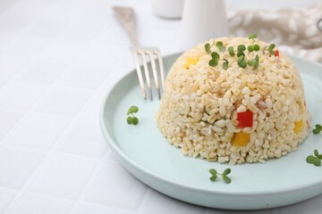 Delicious bulgur with vegetables and microgreens served on table, closeup. Space for text