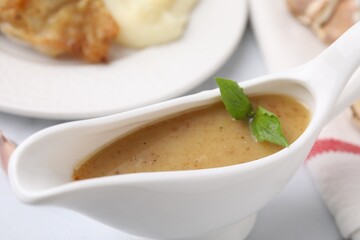 Delicious turkey gravy in sauce boat on table, closeup