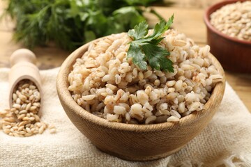 Delicious pearl barley with parsley in bowl on table, closeup