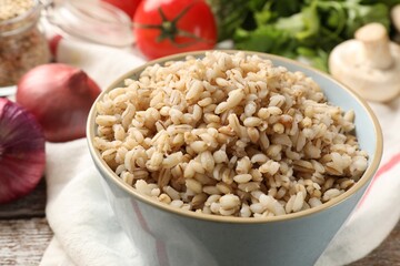 Delicious pearl barley in bowl on table, closeup