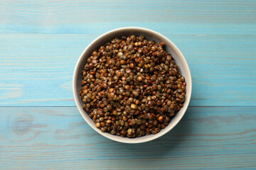 Delicious lentils in bowl on light blue wooden table, top view