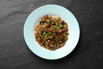 Delicious lentils with mushrooms, bacon and green onion on grey textured table, top view