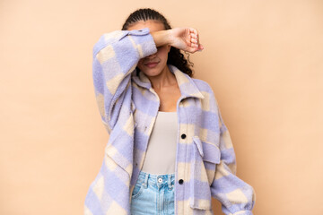 Young woman isolated on beige background covering eyes by hands