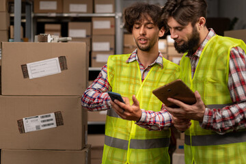 Male warehouse multiethnic workers checking inventory and consulting each other about distribution of goods. Concept of teamwork at warehouse - Powered by Adobe