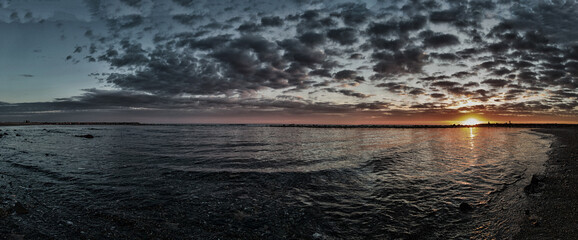 Awesome panoramic 180 degrees of rough sea at sunset, a dramatic sky with amazing light and...