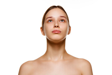 Portrait of beautiful young brunette woman with bare shoulders, well-kept spotless skin looking up isolated white studio background.