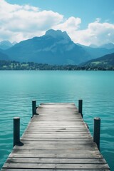 A serene wooden dock on a calm body of water, weathered and worn with age, under a vibrant blue sky. Majestic mountains create a stunning backdrop, making it a perfect nature travel destination