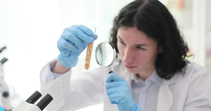 The lab assistant guy looks through the magnifier on the seeds in the flask. Comus suitability for sowing