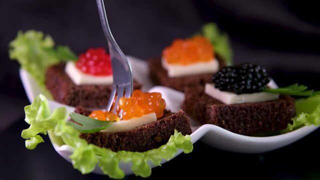 take with a fork a small mini canape sandwich with red caviar and dark Borodino bread different types of red black caviar delicious corporate event rich life living beautifully cannot be prohibited