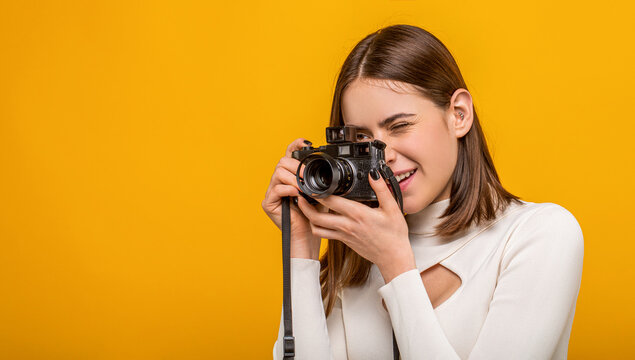 Girl with a cameras. Woman holding camera over yellow background. Girl using a camera photo. Photographing girl make photography taking concept