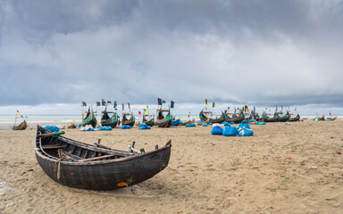 Moody landscape view of traditional wooden fishing boats known as moon boats on beach under cloudy...