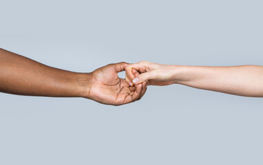 White Caucasian female hands and black african american holding fingers together. Woman and african...