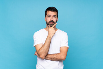 Young man with beard  over isolated blue background thinking