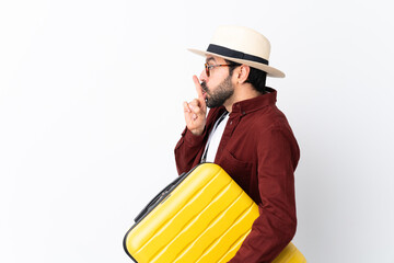 Traveler man man with beard holding a suitcase over isolated white background showing a sign of silence gesture