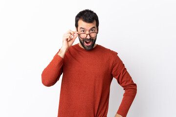 Caucasian handsome man with beard over isolated white background with glasses and surprised