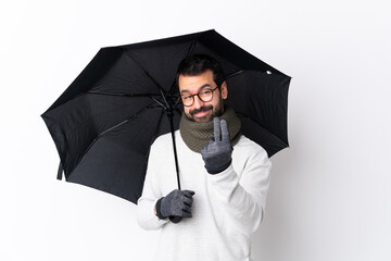 Caucasian handsome man with beard holding an umbrella over isolated white wall inviting to come with hand. Happy that you came