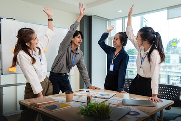 Business team celebrate corporate victory together in office, laughing and rejoicing, smiling excited employees colleague screaming with joy in office